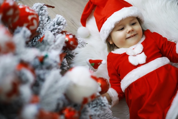 Wesołych jasnych świąt. Urocze dziecko cieszy się świętami Bożego Narodzenia. Wspomnienia z dzieciństwa. Santa dziewczynka małe dziecko świętuje Boże Narodzenie w domu. Rodzinne wakacje. Dziewczyna słodkie dziecko wesoły nastrój grać w pobliżu choinki.