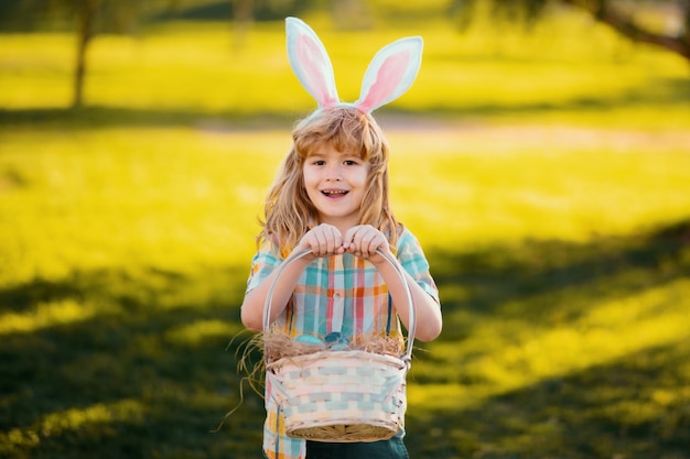 Wesołych świąt dla dzieci chłopiec dziecko w kostiumie królika z uszami królika polującymi na pisanki w parku