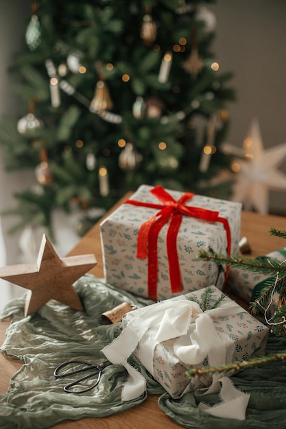 Wesołych Świąt i Szczęśliwych Święt Stylowo zapakowane prezenty bożonarodzeniowe wiejski koszyk z gałęziami sosny i nowoczesnymi dekoracjami na stole w świątecznie ozdobionym skandynawskim pokoju Atmosferyczny obraz