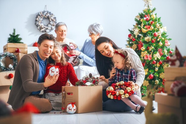 Wesołych Świąt i Wesołych Świąt! Dziadkowie, mama, ojciec i dzieci dekorują drzewko w pokoju. Kochająca rodzina w domu.