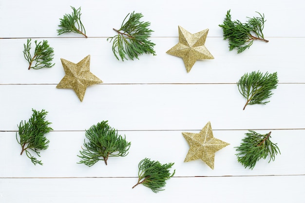 Wesołych Świąt i Wesołych Świąt, świąteczna kompozycja. złote gwiazdy, sosnowe gałęzie na białym tle drewniane.