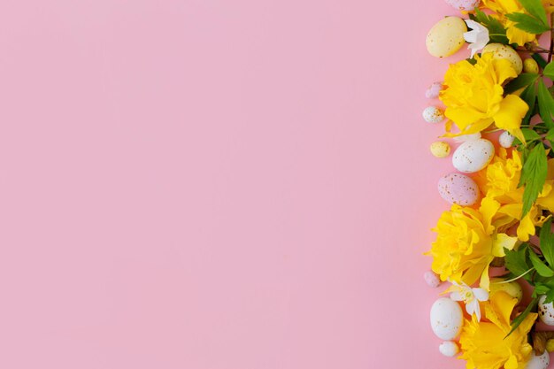 Wesołych Świąt Kolorowe Wielkanocne czekoladowe jajka i żonkile kwiaty granicy na różowym płaskim nieatutowym