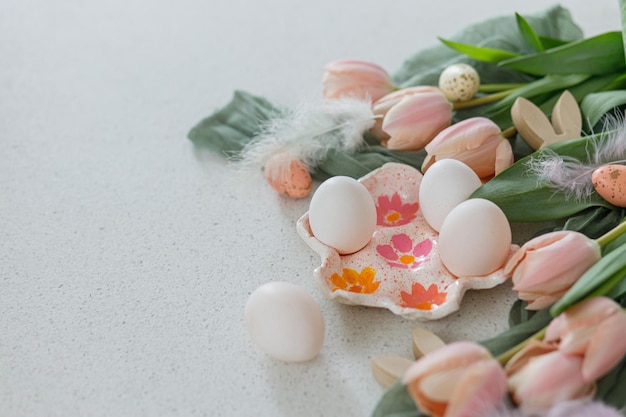 Wesołych Świąt Piękne tulipany naturalne jajka i dekoracja króliczka na nowoczesnym stole Stylowa wielkanocna martwa natura z miejsca na kopię Ręcznie robiona podstawka na jajka różowe tulipany i drewniane uszy króliczka