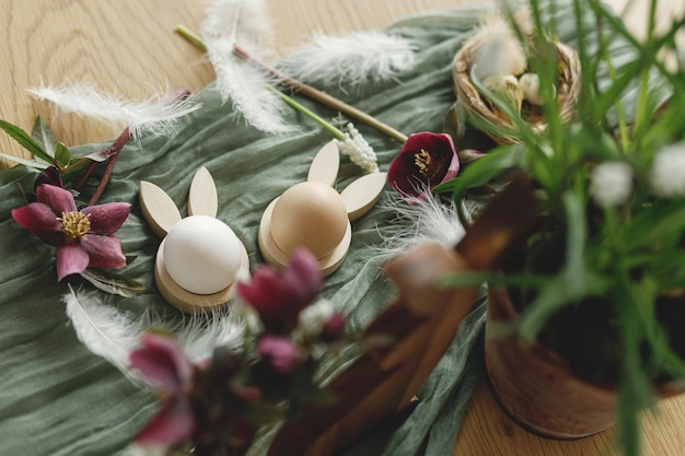 Zdjęcie wesołych świąt stylowe drewniane królicze uszy i naturalne jajka wiosenne kwiaty pióra i gniazdo na rustykalnym stole z bliska wielkanocna martwa natura świąteczna aranżacja i wystrój w wiejskim widoku z góry
