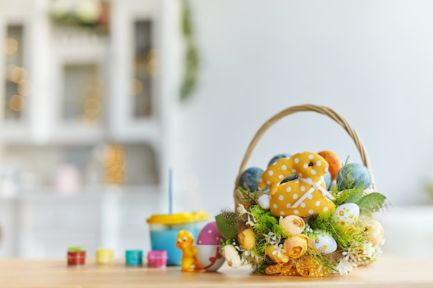 Zdjęcie wesołych świąt wielkanocnych. kolorowe jajka w zdobionym koszu. bejcowany stół, farby i pędzle