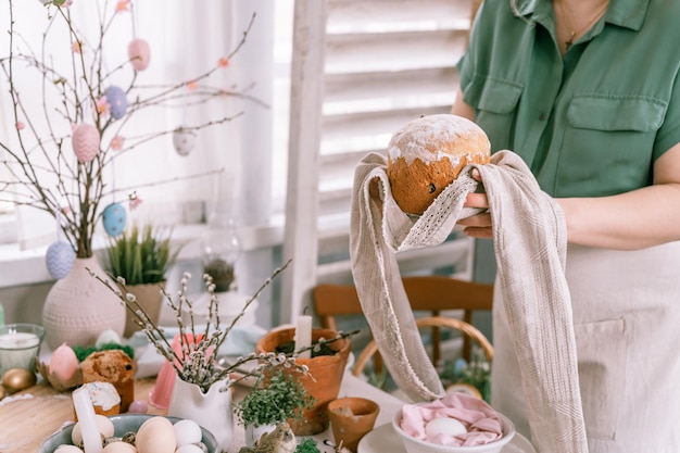 Zdjęcie wesołych świąt wielkanocnych w sezonie wiosennym piękna młoda gospodyni domowa trzyma w dłoniach świeżo upieczone ciasto lub tradycyjny chleb tradycyjne ręcznie robione jedzenie świąteczny wystrój domu