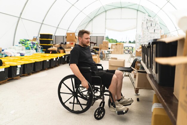 Zdjęcie weteran niepełnosprawny na wózku inwalidzkim pomaga w jednostce humanitarnej wspierającej ofiary wojny