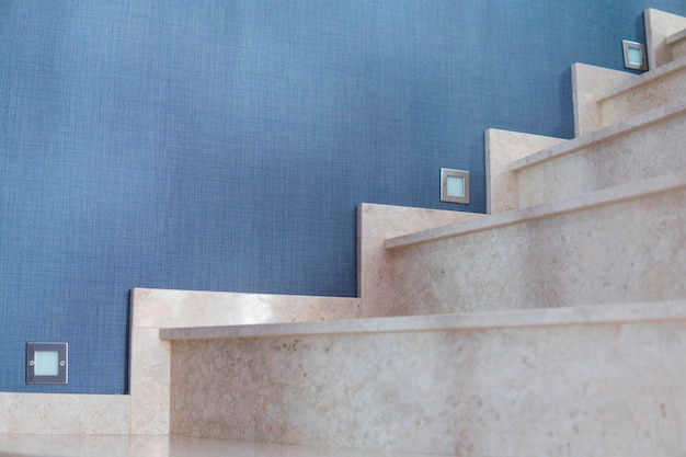 Wewnętrzne marmurowe schody z niebieskim tłem tapety i lekkimi schodami