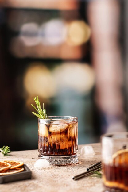 Whiskeycola lub cuba libre mrożone koktajle z rozmarynem i metalowymi słomkami za barem Miejsce na tekst