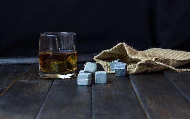 Whisky w szklance z kamieniami do schładzania napojów na drewnianym stole