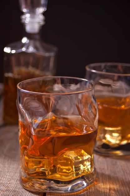 Whisky z lodem na drewnianym stole.