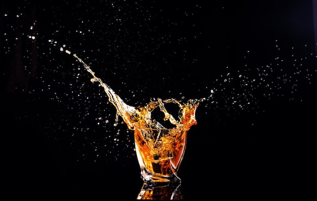 Zdjęcie whisky z pluśnięciem na czarnym tle brandy w szkle