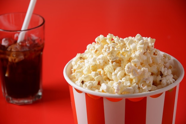 Wiaderka z pysznym popcornem na czerwonym tle i szklanką Coca-Coli