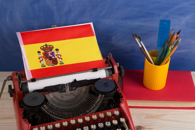 Wiadomości polityczne i koncepcja edukacji czerwona flaga maszyny do pisania hiszpańskiej książki i papeterii na stole