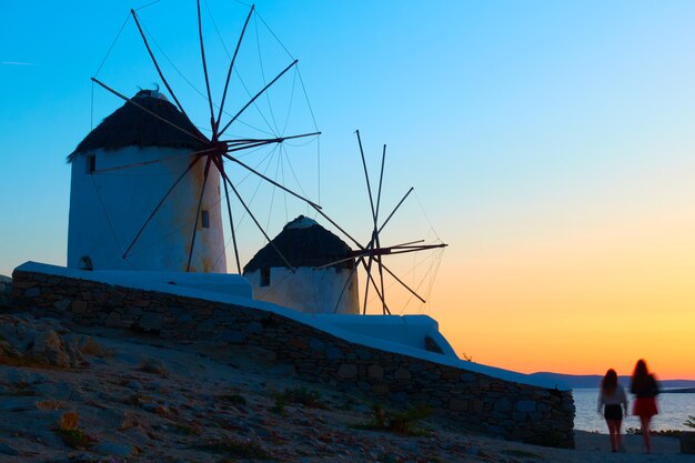 Wiatraki nad morzem na wyspie Mykonos o zmierzchu, Grecja. Grecki krajobraz wiejski