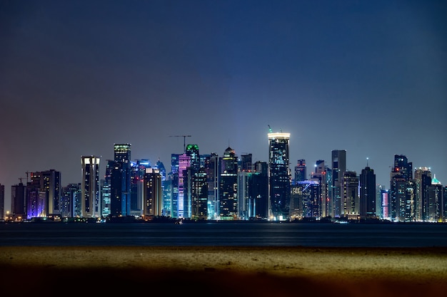 Wibrująca panorama Doha nocą widziana z przeciwnej strony zachodu słońca w zatoce stolicy.