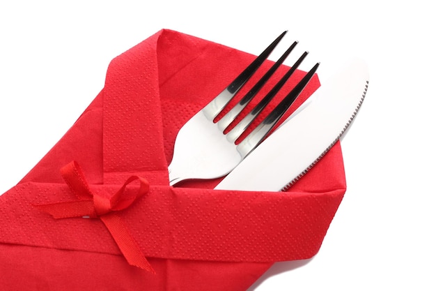 Zdjęcie widelec i nóż w czerwonej tkaninie z łukiem izolowanym na białym