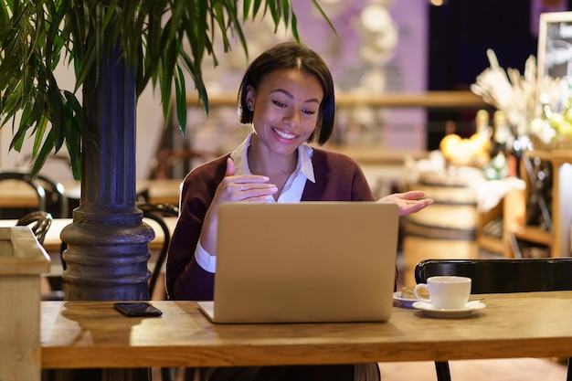 Wideokonferencja spotkanie online z kolegami z szczęśliwą afrykańską bizneswoman pracuje w kawiarni