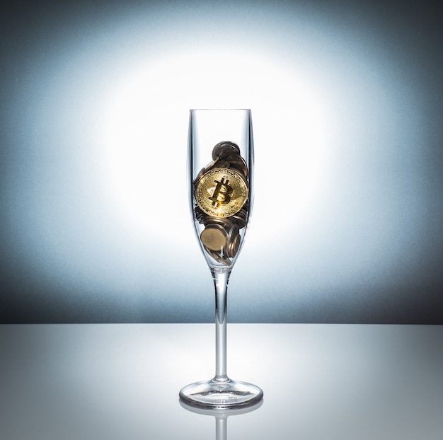 Widok bitcoin w szampańskim szkle wśród inny moneta z białym tłem