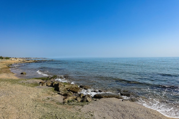 Widok błękitnych fal morskich na kamienistej plaży Linia horyzontu Wybrzeże Morza Kaspijskiego z piaskowca Dagestan