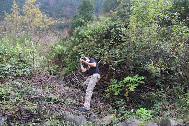 Zdjęcie widok boczny osoby fotografującej za pomocą smartfona w lesie