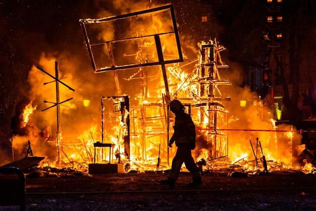 Widok boczny strażaka idącego po lądzie w kierunku spalonych budowli