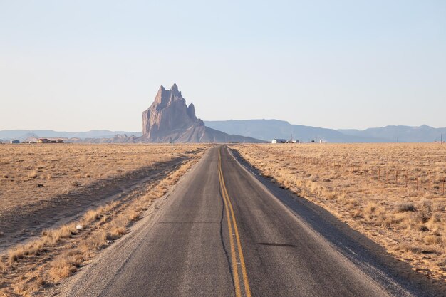 Widok drogi na suchej pustyni z górskim szczytem Shiprock w tle