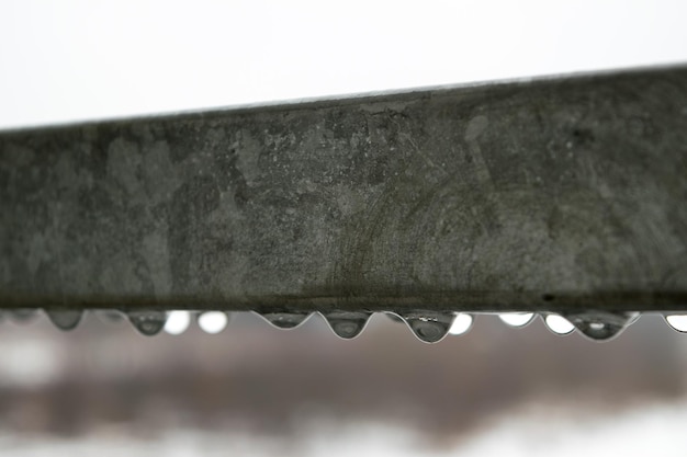 Widok kropelek wody zwisających z metalowej poręczy w deszczowy dzień