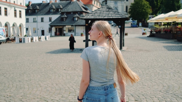 Widok ładna Blondynka Z Tyłu Na Ulicy W Lecie. Ona Idzie Zwiedzać