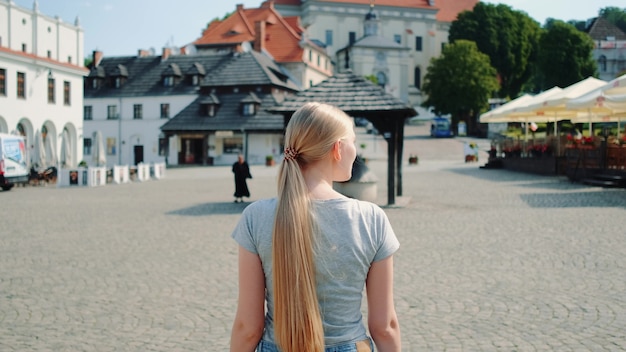 Widok ładna blondynka z tyłu na ulicy w lecie. Ona idzie zwiedzać