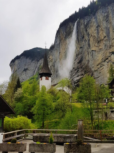 Widok na budynek z drzewami i górami na tle nieba