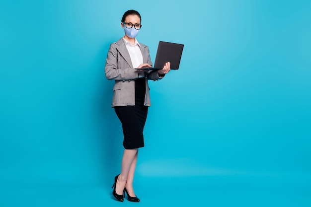 Widok na całą długość ciała eleganckiej pani specjalisty trzymającej w rękach maskę do laptopa na białym tle na jasnoniebieskim tle