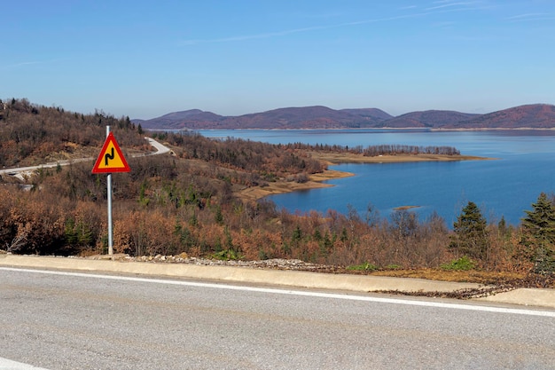 Widok na jezioro Plastiras Tesalia Grecja i znak Niebezpieczny zakręt z pierwszym zakrętem do