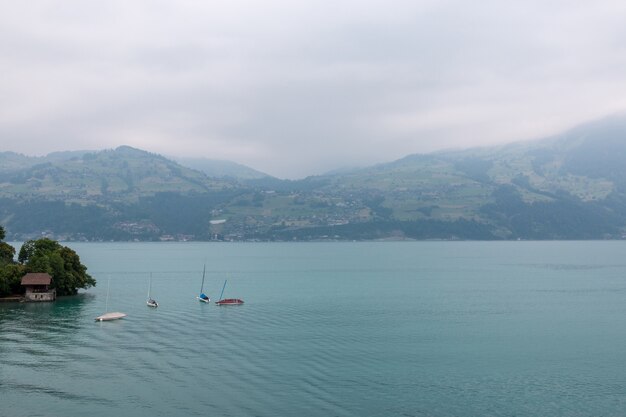 Zdjęcie widok na jezioro thun i góry ze statku w mieście spiez, szwajcaria, europa. letni krajobraz. dramatyczna, nastrojowa scena z niebieskimi chmurami