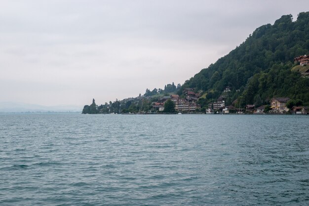 Widok na jezioro Thun i góry ze statku w mieście Spiez, Szwajcaria, Europa. Letni krajobraz. Dramatyczna, nastrojowa scena z niebieskimi chmurami