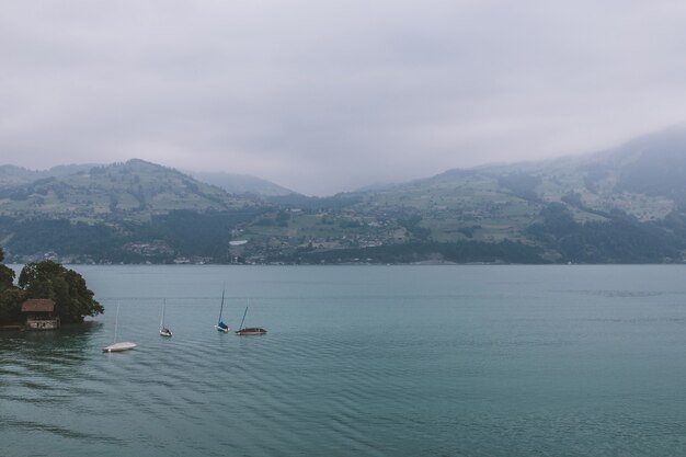 Widok na jezioro Thun i góry ze statku w mieście Spiez, Szwajcaria, Europa. Letni krajobraz. Dramatyczna, nastrojowa scena z niebieskimi chmurami