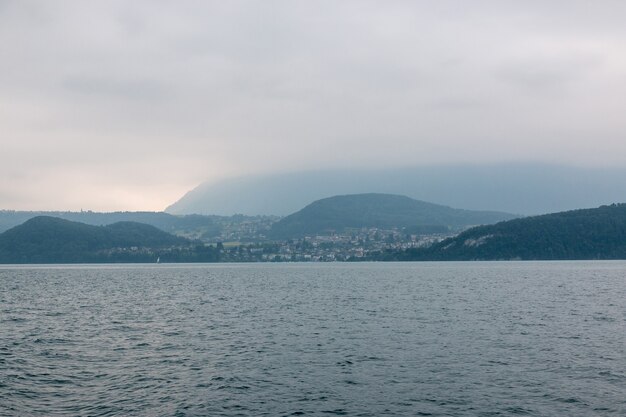 Widok na jezioro Thun i góry ze statku w mieście Spiez, Szwajcaria, Europa. Letni krajobraz. Dramatyczna, nastrojowa scena z niebieskimi chmurami