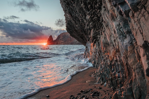 Widok na morze o zachodzie słońca i plażę, skałę wulkaniczną, piasek i kamyki, wulkaniczny bazalt jak na Islandii. Skopiuj miejsce. Pojęcie spokoju, ciszy i jedności z naturą. Fiolent Sewastopol, Krym