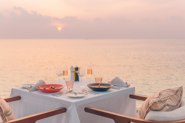 Widok na morze, światło zachodu słońca ze stołem jadalnym z odbiciem basenu bez krawędzi. Romantyczny wypad dla par