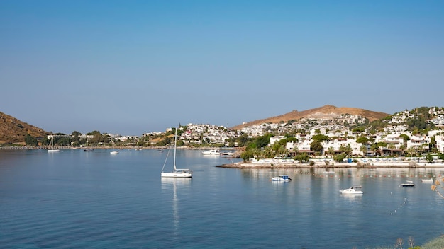 Widok na plażę Bodrum Morze Egejskie tradycyjne białe domy kwiaty marina łodzie żaglowe jachty w mieście Bodrum Turcja