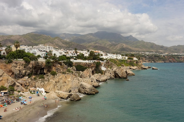 Zdjęcie widok na plażę nerja z balcon de europa z burzowymi chmurami nad górami