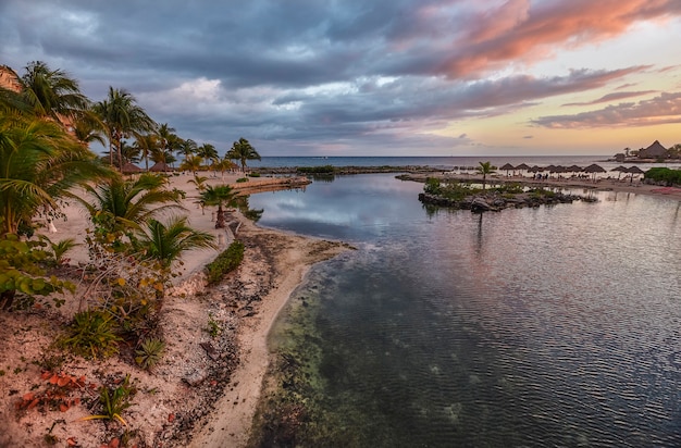 Zdjęcie widok na plażę puerto aventuras na riwierze majów w meksyku pokrytą mrocznym niebem z kontrastami niebieskiego, fioletowego i pomarańczowego.