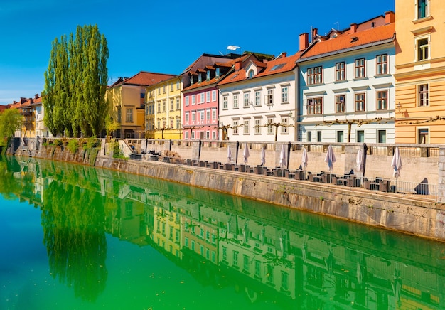 Widok na rzekę Ljubljanica w centrum Lublany. Kolorowe historyczne budynki odbijające się w wodzie