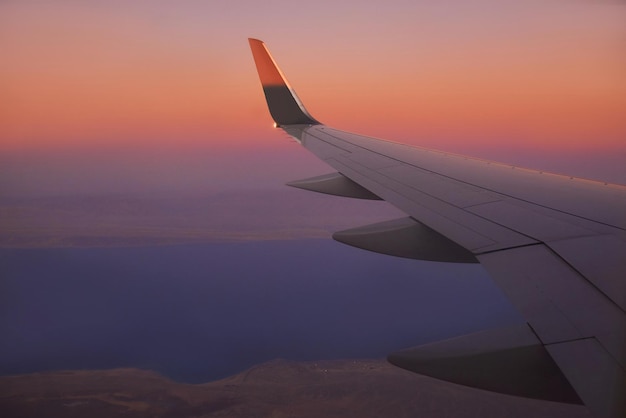 Widok na skrzydło samolotu na niebie podczas zachodu słońca