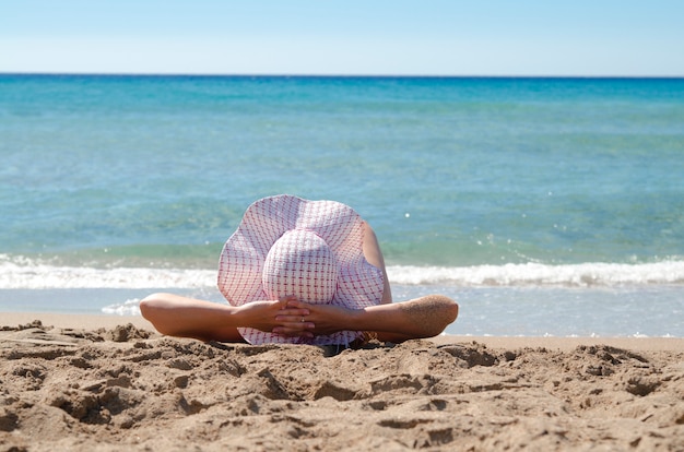 Widok Na Słońce Kapelusz Na Głowie Dziewczyny I Jej Ramionach Cieszyć Się Opaleniem I Oglądać Morze.woman Leżał Na Piaszczystej Plaży I Oglądać Wodę Morską.