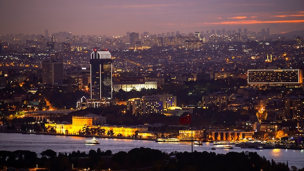 Widok na Stambuł nocą, iluminacje wielokrotne, budynki niskie i wysokie, cieśnina Bosfor na pierwszym planie, Turcja