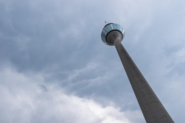 widok na wieżę renu (Rheinturm) z dramatycznym pochmurnym niebem w dusseldorfie w niemczech. idealny do układów stron internetowych i czasopism