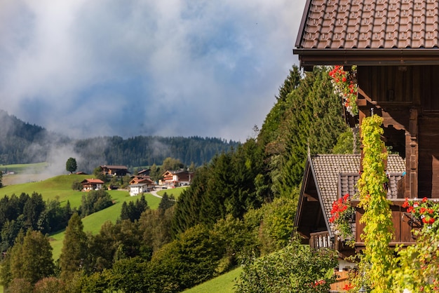 Widok na zieloną łąkę w górach z typowej drewnianej wioski balkonowej w Alpach Austria