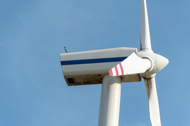 Widok nowoczesnego wiatraka na tle błękitnego nieba Białe łopaty turbiny wiatrowej z bliska Odnawialne źródło energii Produkcja taniej i bezpiecznej energii elektrycznej
