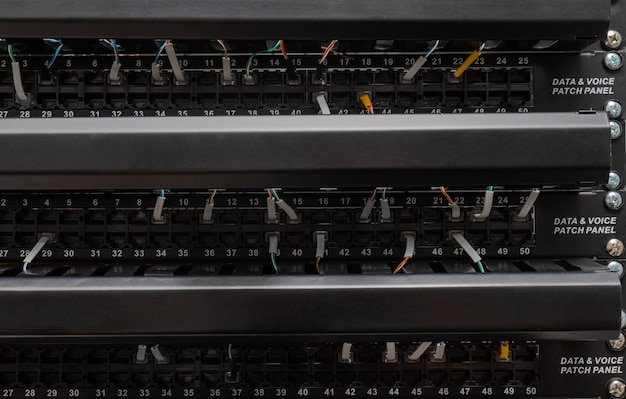 Widok panelu krosowania danych głosowych z podłączonymi wieloma kablami. Koncepcja komunikacji i sieci